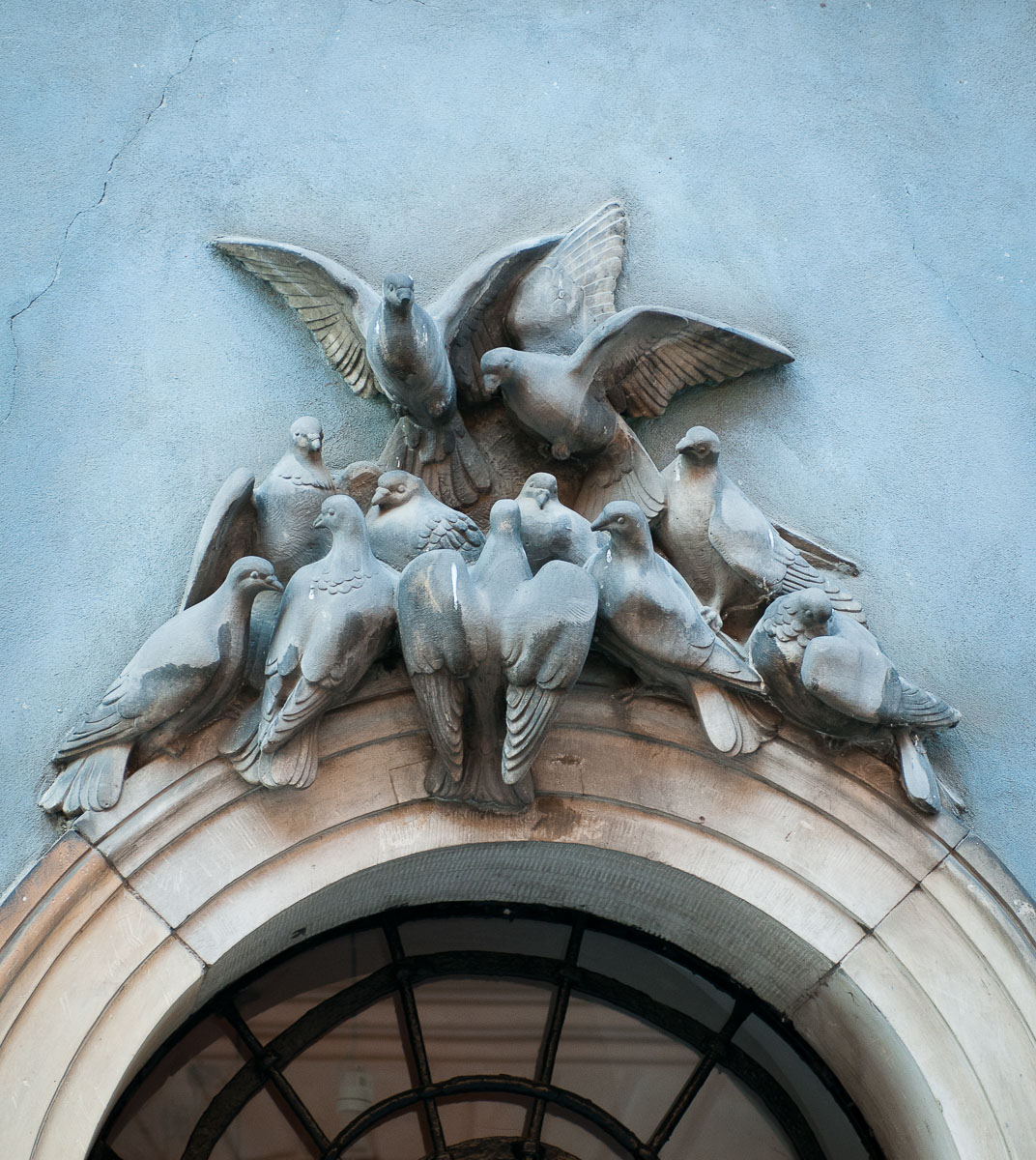 Rzeźba tłoczących się gołębi nad drzwiami